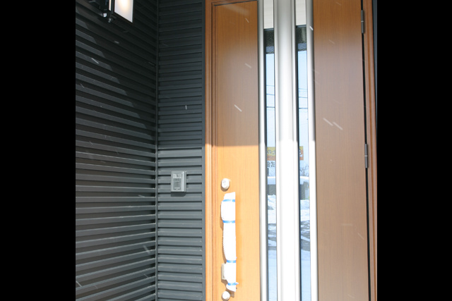 玄関ドア： 板金の壁に、スタイリッシュな デザインのドアが合います。