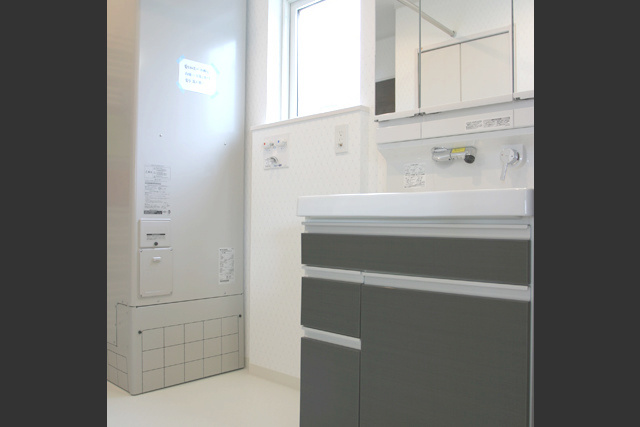 電気温水器： 電気温水器と洗面化粧台。 置き場所に困る体重計は、 化粧台下部の引出しに収納。