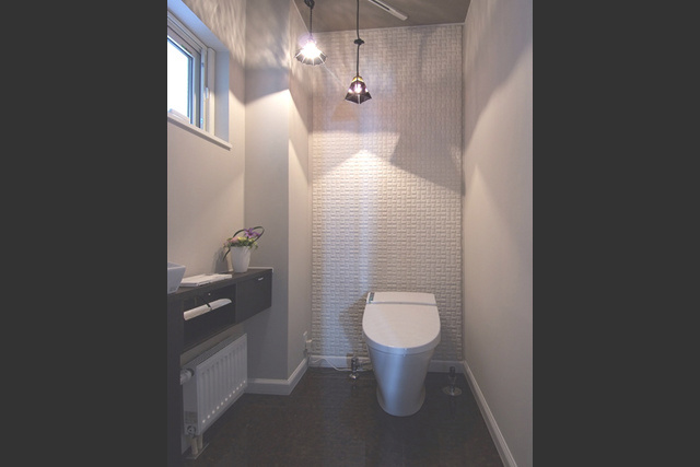 トイレ： エコカラットタイルの凹凸と ランプシェードの影が美しい。